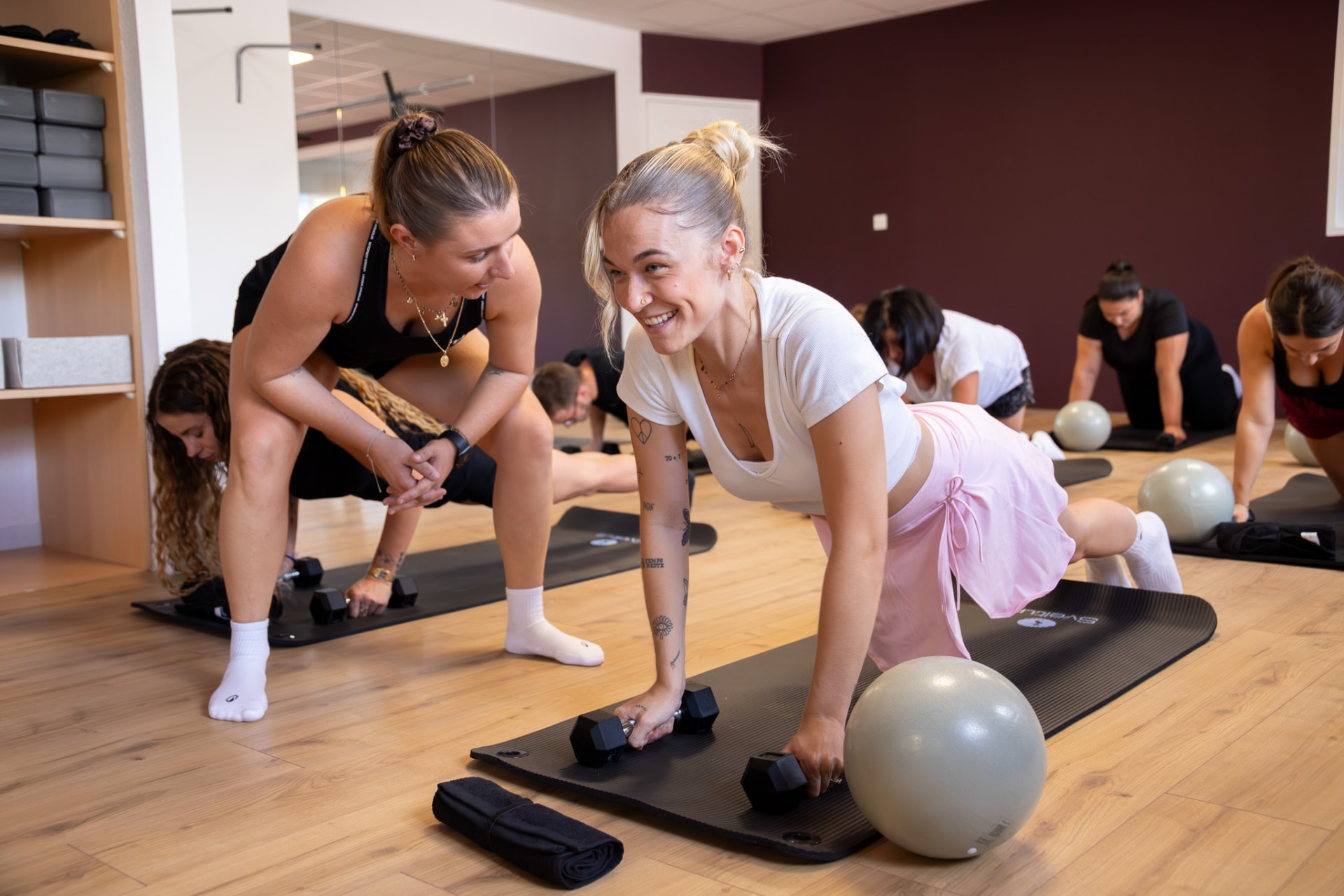 Cours collectif au studio KINŌ : coach accompagnant une pratiquante sur tapis