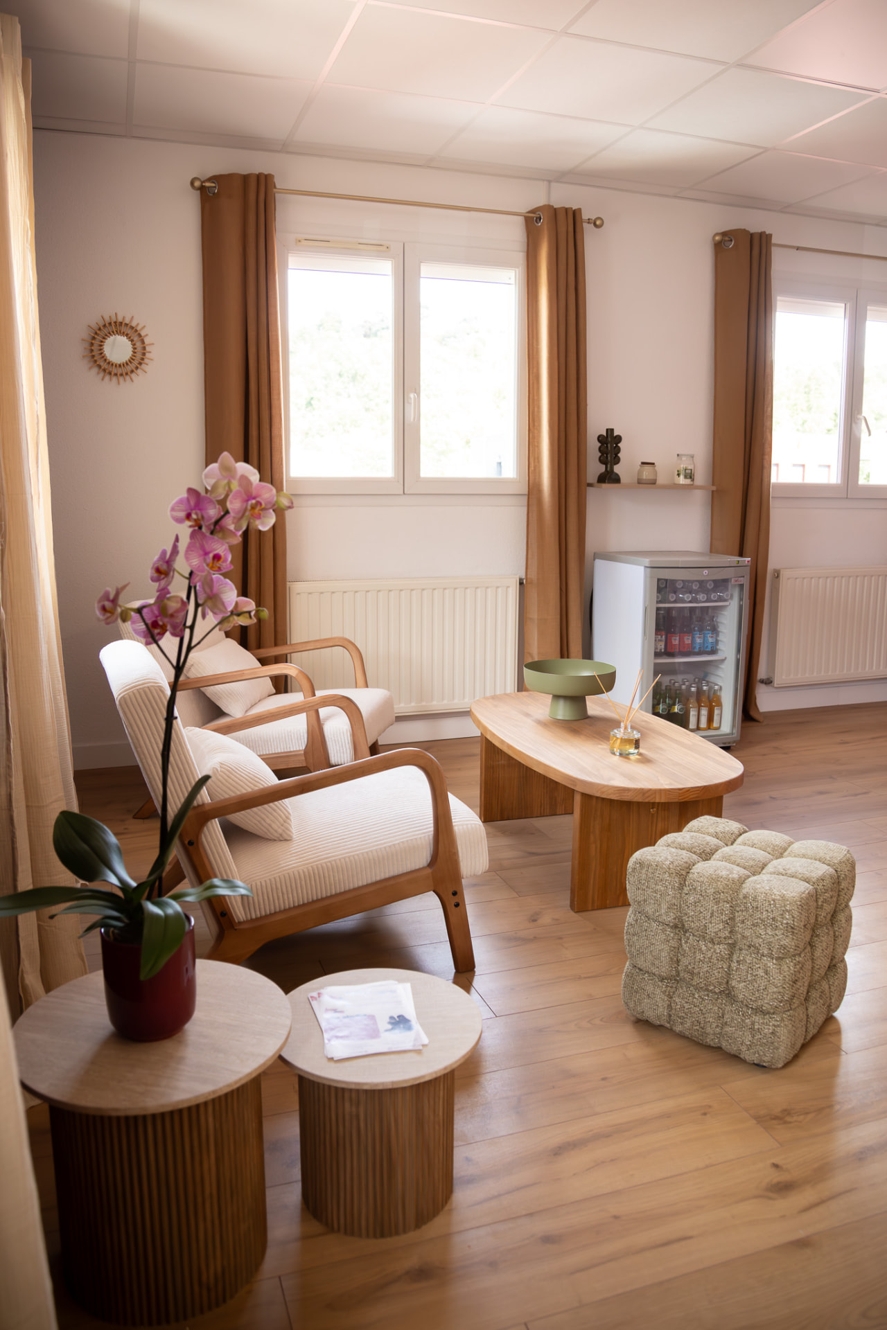 Espace détente du studio KINŌ : fauteuils crème, table basse en bois et orchidée