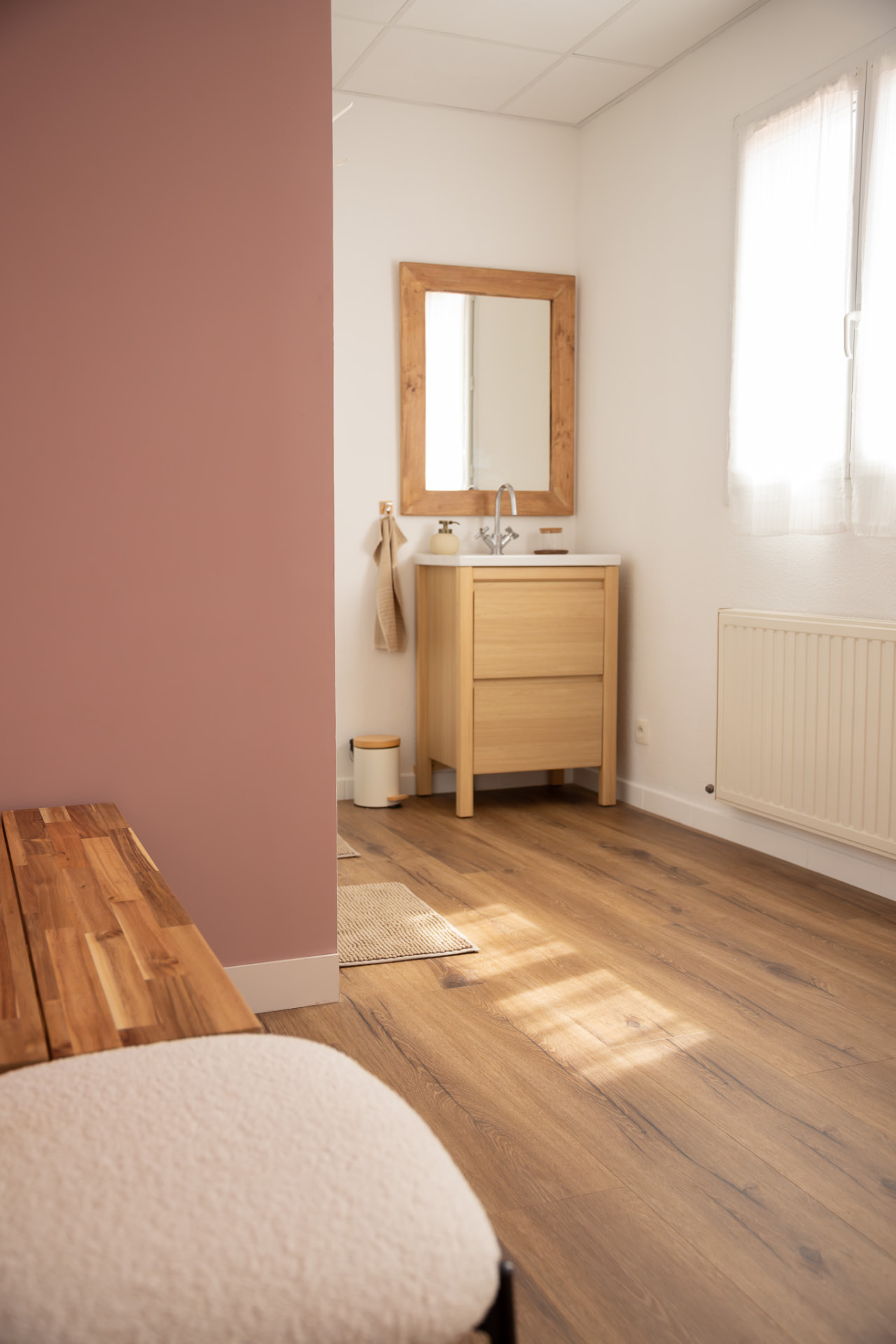 Vestiaire du studio KINŌ avec lavabo en bois, miroir et mur rose
